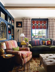 a living room filled with furniture next to a window covered in colorful pillows and curtains