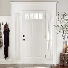 a white door with two hooks on the side and a tree trunk in front of it