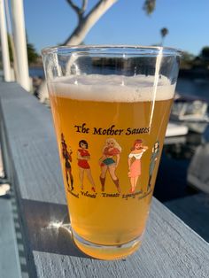 a pint glass sitting on top of a wooden table next to a body of water