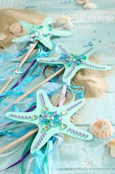 several starfish and seashells on the beach with blue streamers, sand and shells