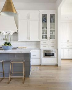 a kitchen with white cabinets and an island in the middle is lit by a pendant light