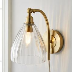 a wall light with a glass shade on it's arm and the bulb turned off