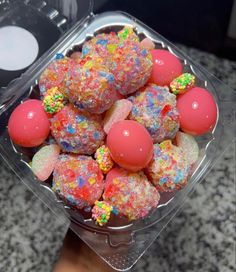 a plastic container filled with lots of colorful candy covered in sprinkles on top of a counter