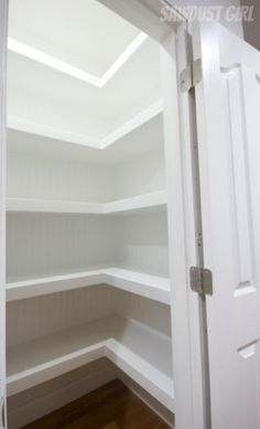 an empty closet with white walls and wood floors