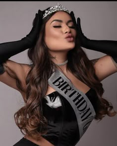 a woman wearing a tiara and gloves posing for the camera with her hands on her head