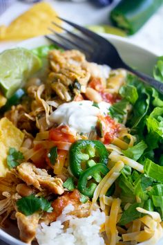 a white plate topped with chicken, rice and veggies next to a fork