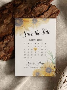 save the date card with sunflowers on it next to a piece of wood