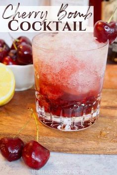 cherry bomb cocktail in a glass with ice and cherries on the table next to it