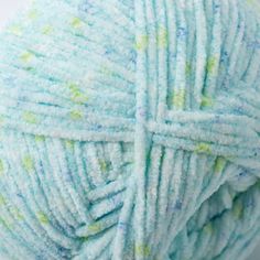 a ball of blue yarn with green and white speckles on the end is shown