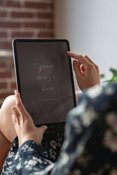 a woman is holding an electronic device in her hands and pointing to the screen that reads your design line