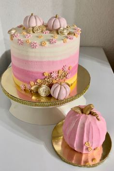 there is a pink and yellow cake on the plate next to it, with two small pumpkins