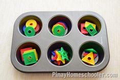 a muffin tin filled with plastic toys on top of a wooden table