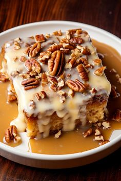 a piece of cake with pecans on top and caramel sauce drizzled over it