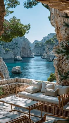 an outdoor seating area overlooks the water and rocky cliffs, which are surrounded by pine trees