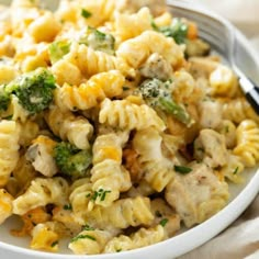 a white bowl filled with macaroni and broccoli on top of a table