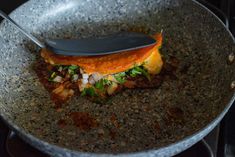 a pan filled with food and a spatula on top of the stove burner