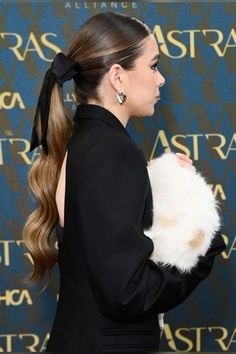 a woman with long hair wearing a ponytail and holding a fluffy ball in her hand