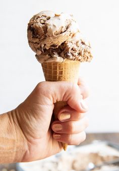 a hand holding an ice cream cone filled with chocolate