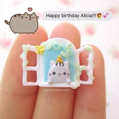 a hand holding a tiny white cat with a birthday hat on it's head