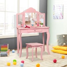 a child's pink desk and chair in a room with balls on the floor