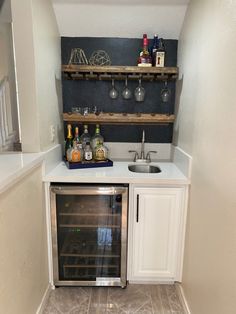 a small kitchen with an oven, sink and wine glasses on the shelf above it