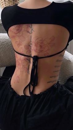 a woman with tattoos on her back sitting in a chair