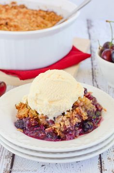 a white plate topped with fruit cobbler next to a bowl filled with ice cream