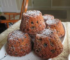 four muffins on a white plate with powdered sugar and raisins