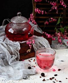 a tea pot and glass on a table with pink flowers