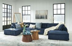 a living room with blue couches and pillows on the floor in front of large windows