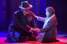 a man in a suit and tie sitting on the ground next to a woman wearing a hat