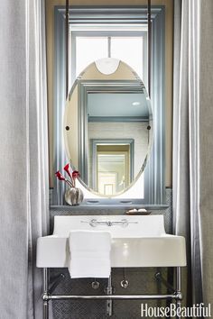 a bathroom sink sitting under a mirror next to a window with drapes on it