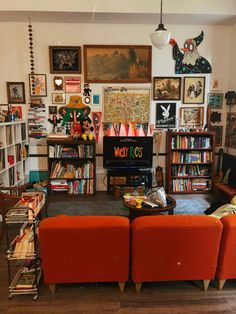 a living room filled with orange couches and bookshelves next to a flat screen tv