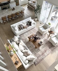 an aerial view of a living room with white furniture and large windows overlooking the kitchen