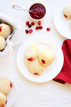 cranberry filled pastries on white plates next to red napkin and bowl of jam