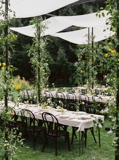 an outdoor dining area with tables and chairs set up for a formal dinner in the garden