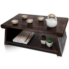 a coffee table with bowls and cups on it, next to a potted plant