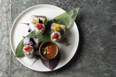 a white plate topped with sushi and dipping sauce