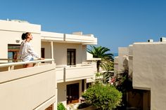 a woman standing on top of a balcony next to an apartment building near the ocean