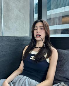 a woman sitting on top of a couch wearing a black and white shirt with her mouth hanging out