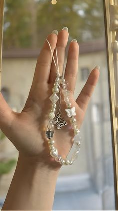 a woman's hand holding several bracelets in front of a window