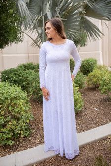 a woman wearing a white dress standing on a sidewalk