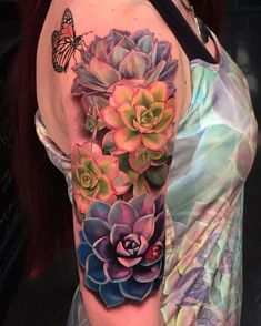 a woman's arm with a flower and butterfly tattoo on her left arm, which is covered in succulents