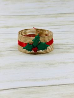 two christmas bracelets with holly leaves on them sitting on a white wooden table top