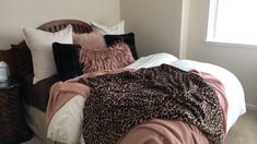 a leopard print blanket is on top of a bed with pillows and blankets in the corner