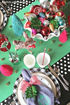 a table set for christmas with plates, silverware and ornaments