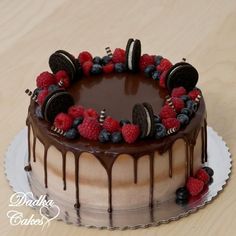 a chocolate cake with raspberries and oreo cookies on top, drizzled in chocolate