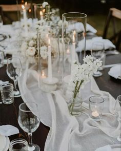 the table is set with candles and flowers in glass vases on top of it