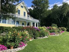 a yellow house with many flowers in the front yard