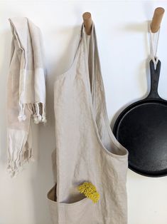 an apron hanging on the wall next to a frying pan with a yellow flower in it